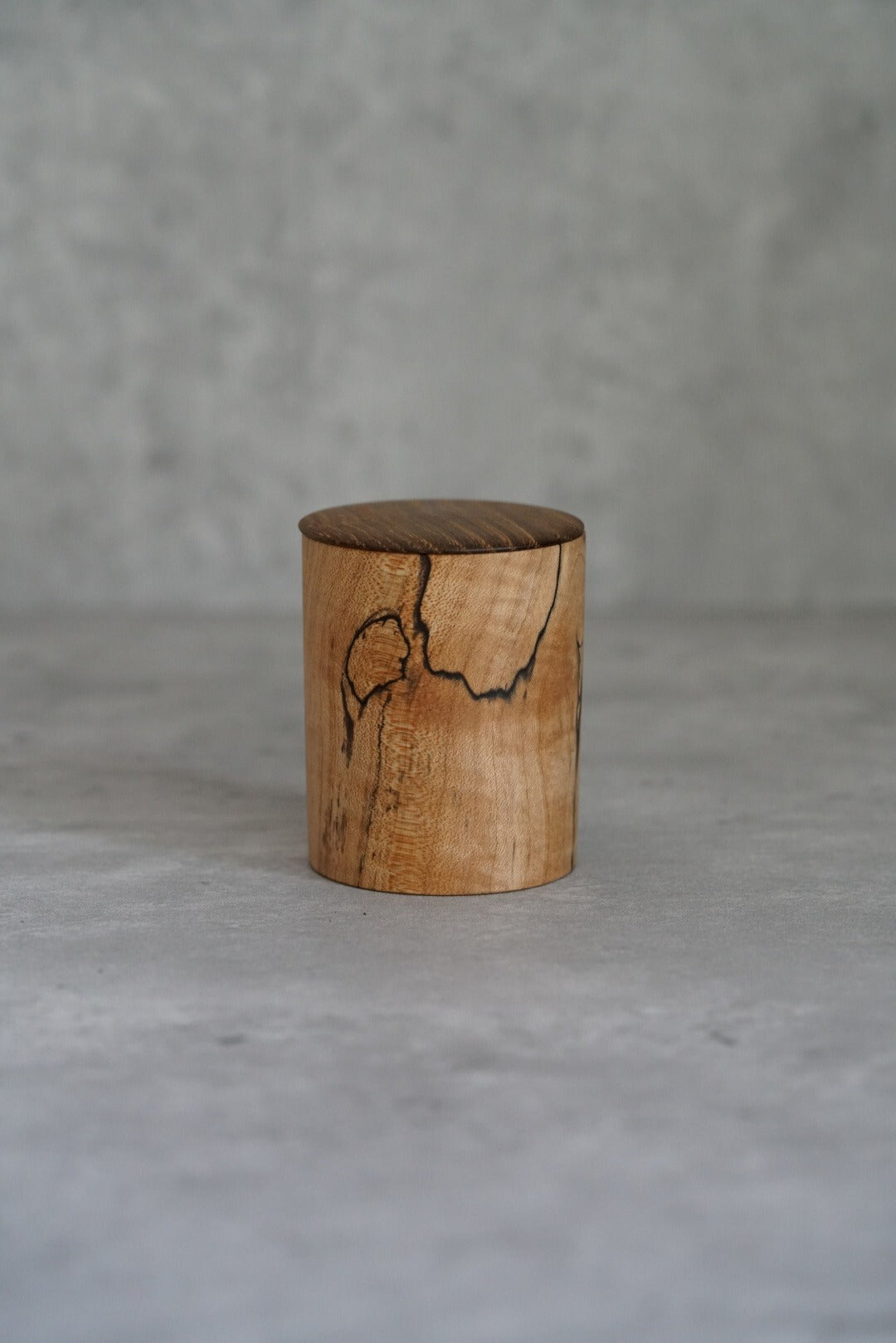 Small lidded wooden jar turned from pale maple, with a dark natural crack across the lid.