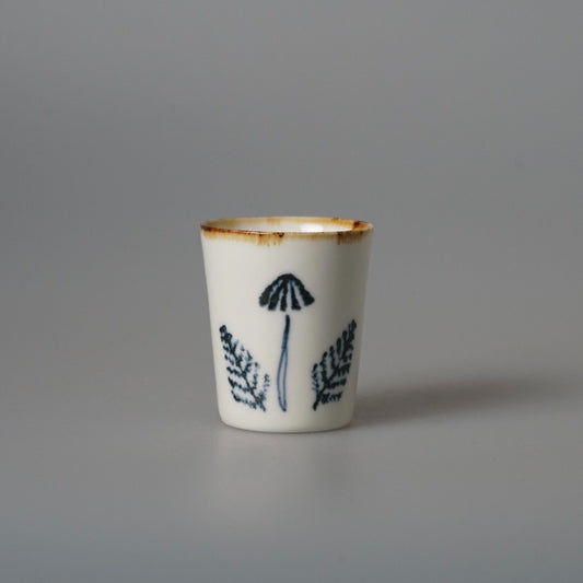 Small white cup with a gold-brushed rim, painted with blue seed heads and grass stems.