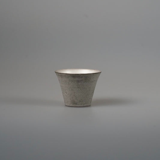 Small flared cup in matte grey clay with a soft silver sheen around the rim.