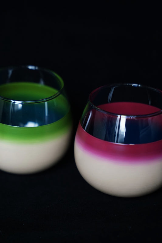 Two glossy lacquer cups with cream lower halves, one topped in bright green and the other in deep pink.