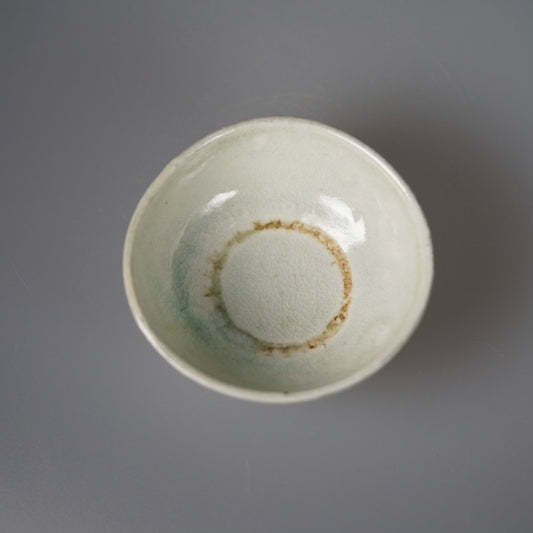 Shallow bowl seen from above, pale green glaze ringing a cream pool at its centre.