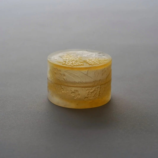 Small round pale yellow glass box, its lid crusted with a frosted blossom-like texture.
