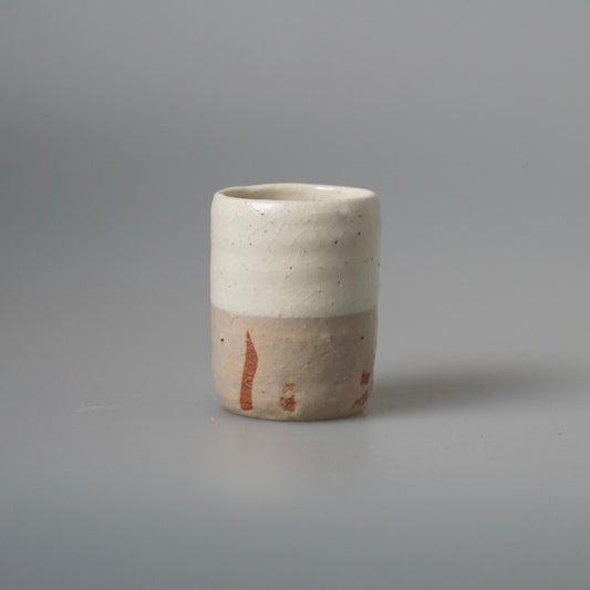 Tall cream cup with soft orange flame marks running down from the rim.