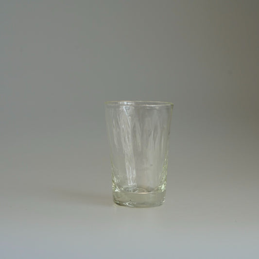 Tall glass tumbler with a rippled dimpled surface and a faint yellow-green cast.