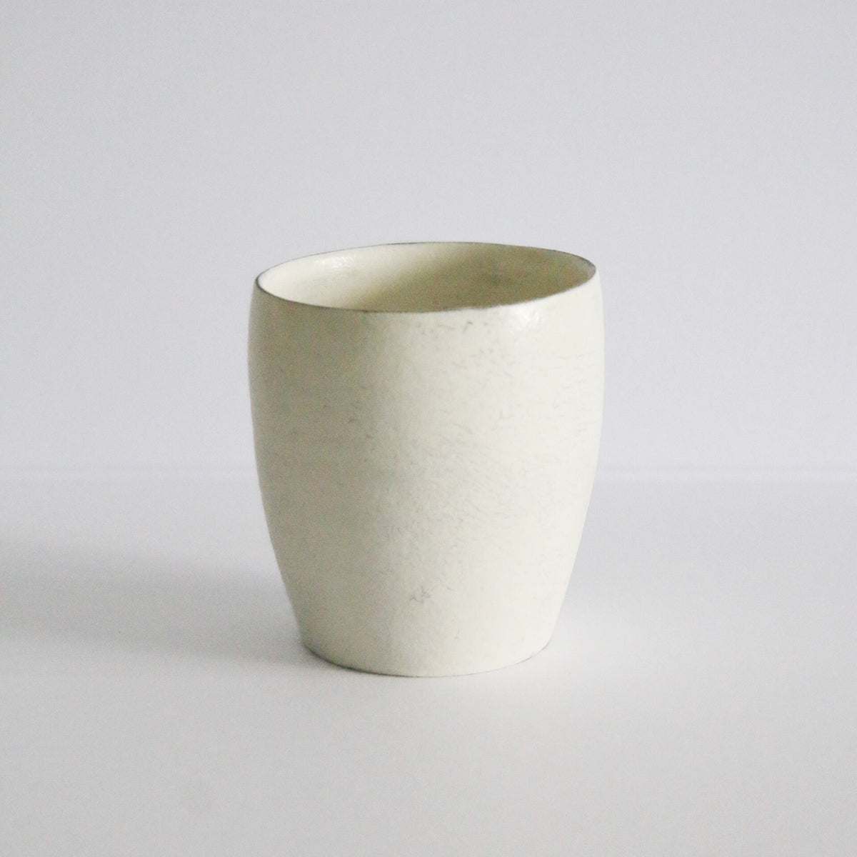 Tall straight cream cup with a soft chalky surface and a slightly narrowed base, on white.
