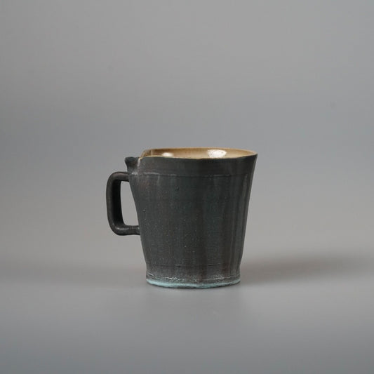Faceted mug in dark grey with a pale glazed interior and a square-cut handle.