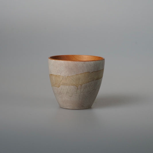 Plant-dyed wooden tea cup in pale stone grey with a warm orange lacquered interior.