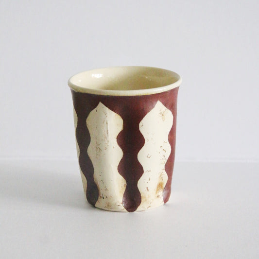 Straight-sided cream cup painted with deep red panels between pale arch shapes.