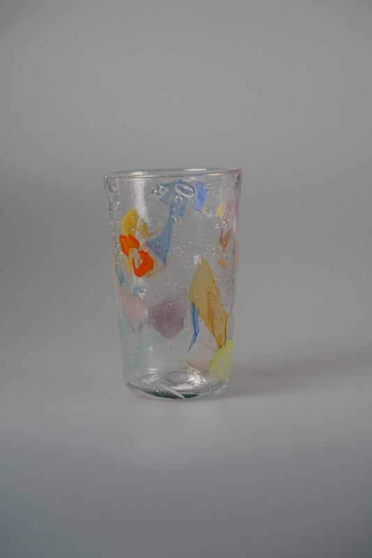 Tall clear glass tumbler dabbed with soft pink, yellow and blue colour marks.