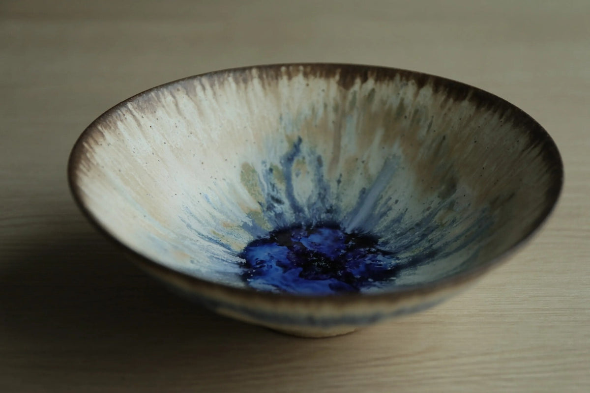 Wide shallow tea bowl, cream and olive glaze streaming down the sides to a deep blue pool at the centre.