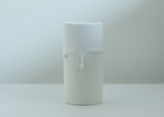 Tall cylindrical white vase, its glaze running down the side in two thick drips.