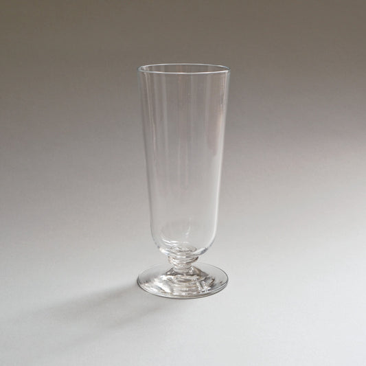 Tall stemmed glass with a slender ribbed foot and a plain flared bowl, on white.
