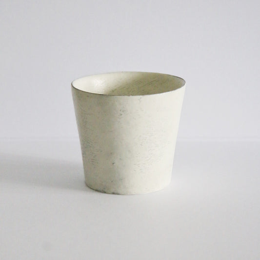 Tapered cream cup with a chalky matte surface and a clean thin rim, on white.