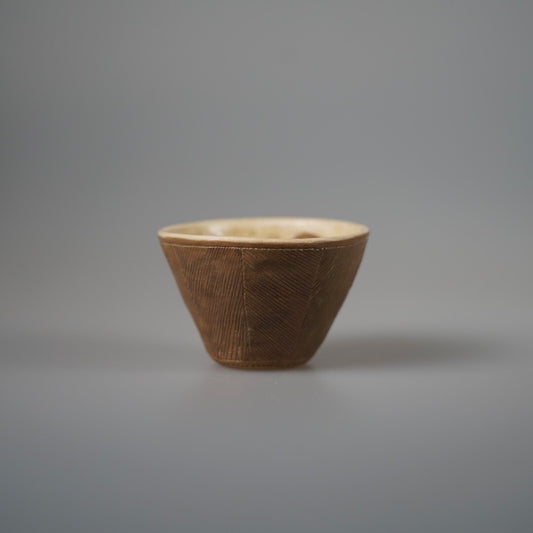 Conical cup with a finely combed brown outer wall and a pale glazed interior.
