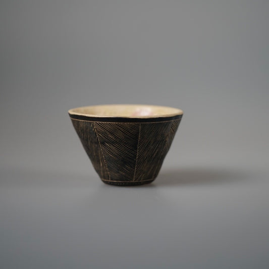 Conical cup with a dark combed outer wall and a warm cream glazed interior.