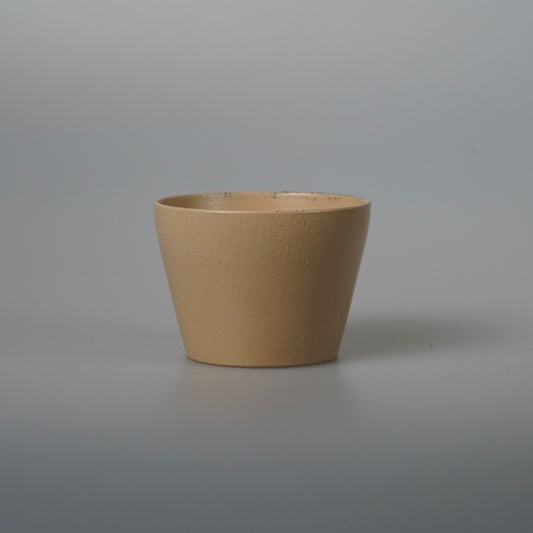 Tapered wooden tea cup in soft matte cream lacquer, lit against a plain grey ground.