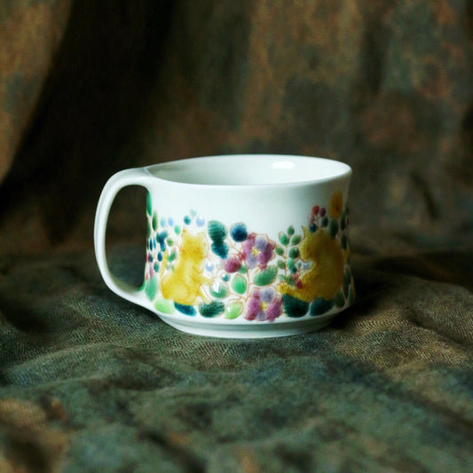 White porcelain mug painted with a band of small bright flowers around its middle.