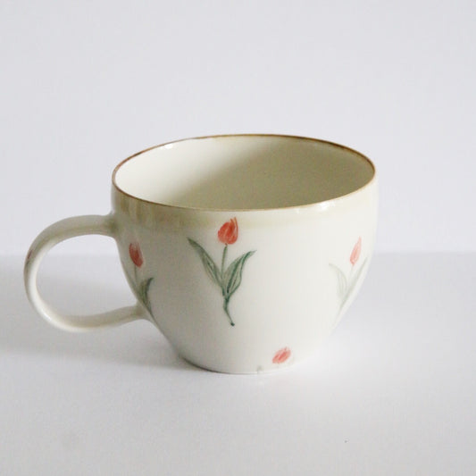 Cream mug with a gold-brushed rim, painted with small orange tulips on slender green stems.