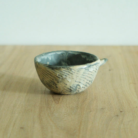 Low wide cup with a single pointed lug, carved in fine feathered lines under a green glazed rim.