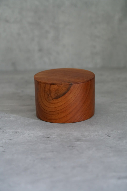 Squat lidded wooden jar in glossy amber lacquer, its grain sweeping across the rounded lid.