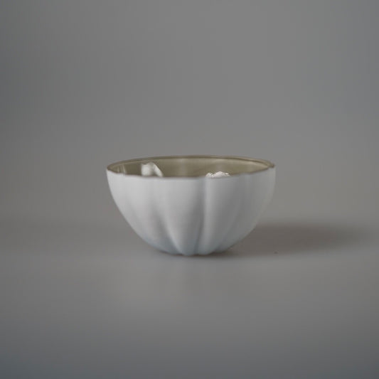 Small frosted white glass bowl with softly fluted sides, on a pale grey ground.