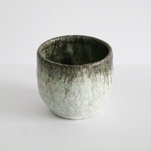 Straight-sided cup with a crusty cream glaze breaking to warm brown around the rim.