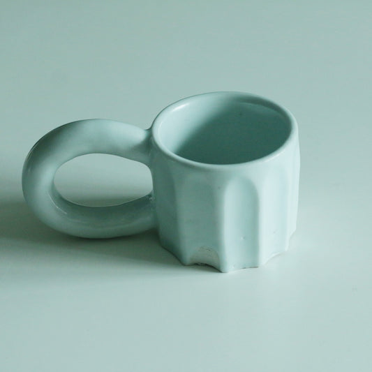 Pale celadon mug with a rippled body and a wide flat ring handle at its side.