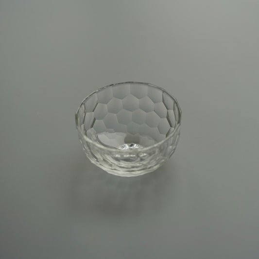 Small clear glass bowl cut all over in a honeycomb of shallow round facets.