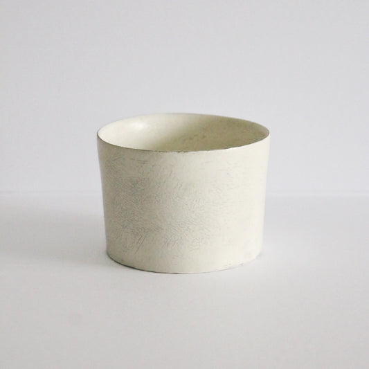 Wide low cream cup with straight sides and a chalky matte surface, on white.
