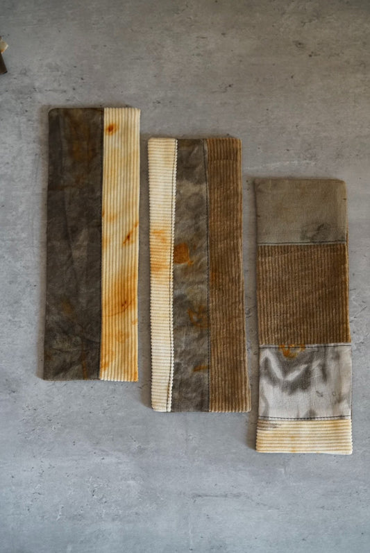 Five long strips of hand-dyed cloth in grey, rust and cream, laid side by side.