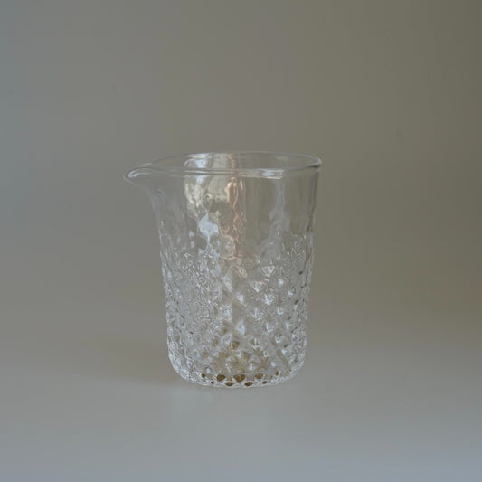 Clear glass pourer with a diamond-cut lower body and a wide drawn lip.
