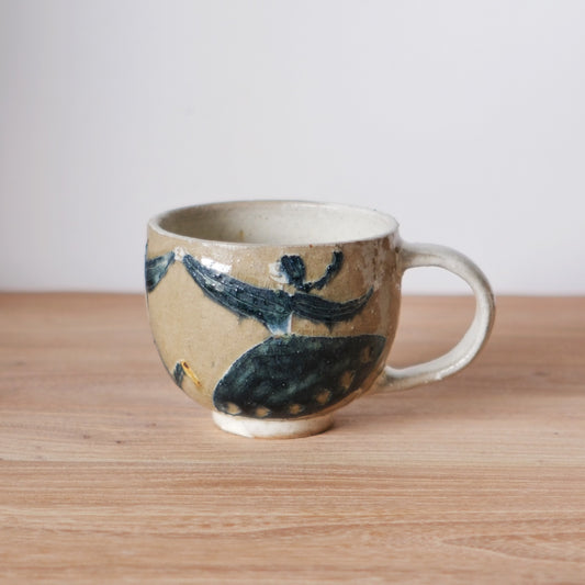 Cream ceramic mug with a chunky handle, painted with bold navy leaves and small dots.