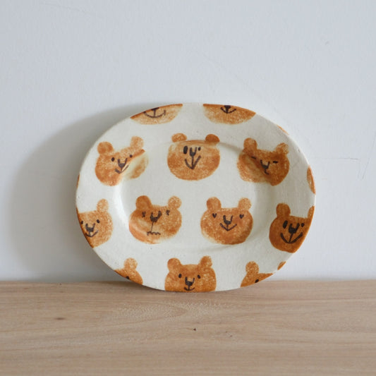 Oval white plate covered edge to edge with rows of small painted brown bear faces.