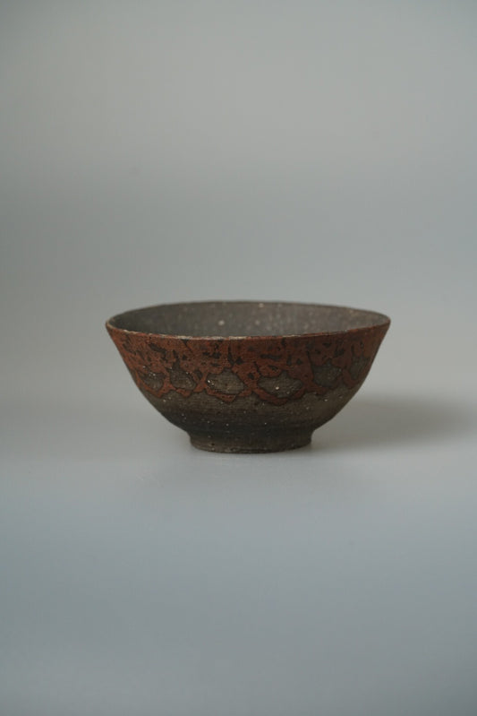 Shallow wood-fired bowl in dark speckled brown with a coarse rough surface.