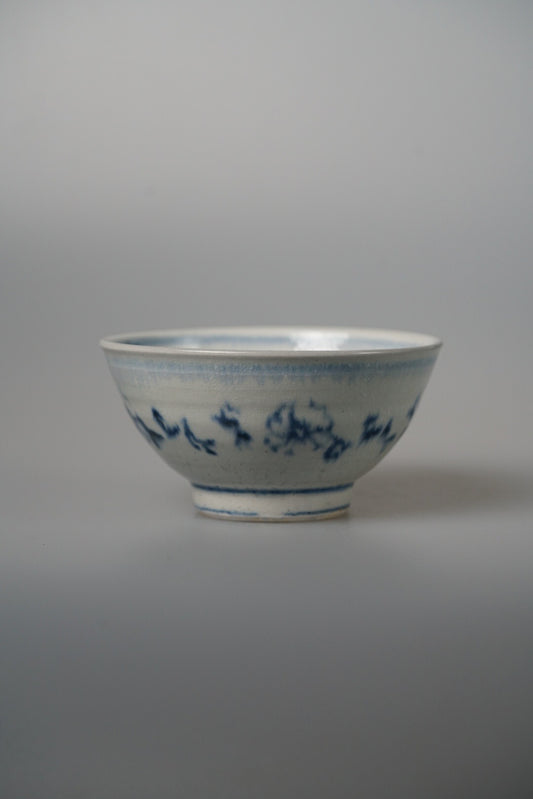 Footed white bowl painted with a delicate blue floral band running around its rim.