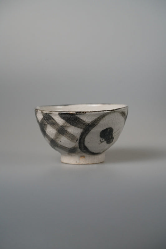 Cream bowl painted with a bold black check panel and a dark rounded motif.