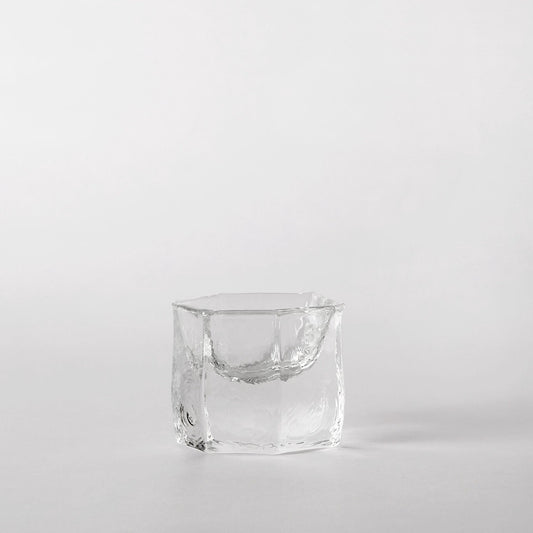 Small squared clear glass cup with a folded lip and thick, softly rippled walls.