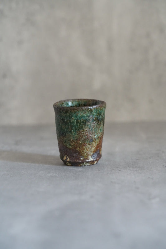 Small footed cup in mottled green and copper glaze, on a pale grey ground.