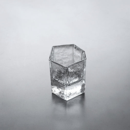 Tall squared clear glass cup with thick angled walls and a slightly uneven rim.
