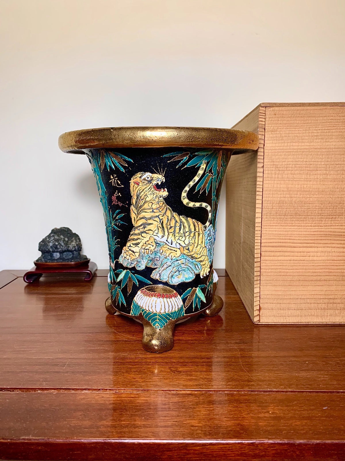 Black glazed pot with gold tiger and bamboo, three feet, brass rim.