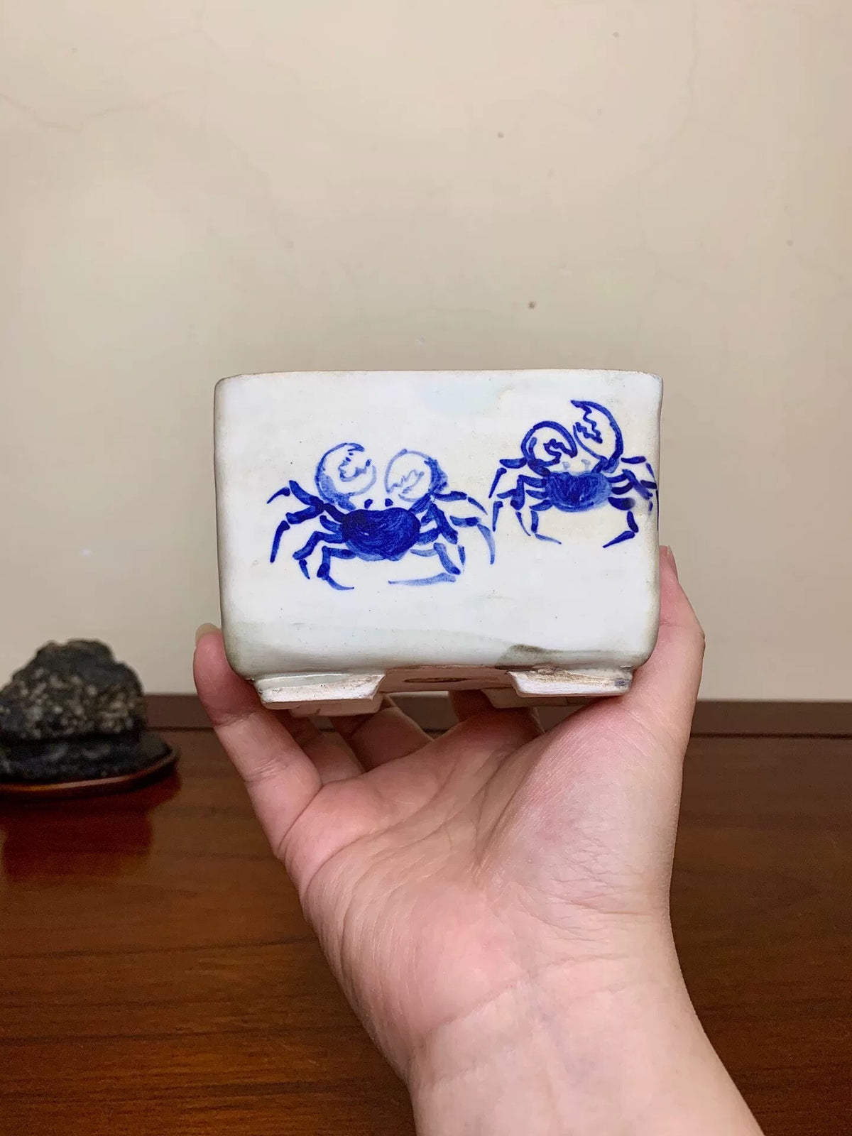 A white glazed rectangular pot with two blue painted crabs on its side.