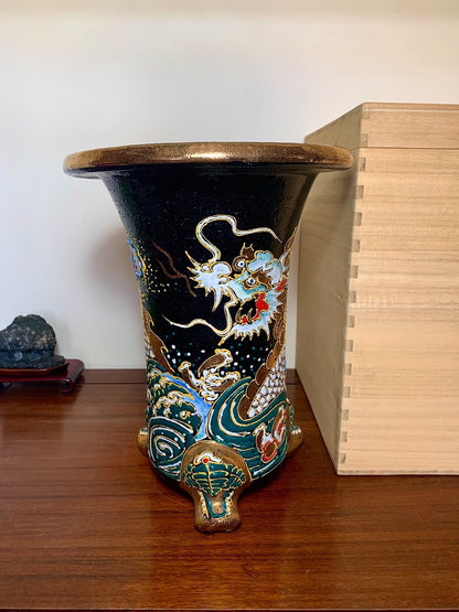 Black glazed pot with gold and blue dragon decoration, three feet, wide rim.