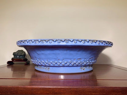 A wide, shallow blue glazed pot with a scalloped rim and raised dot decoration.
