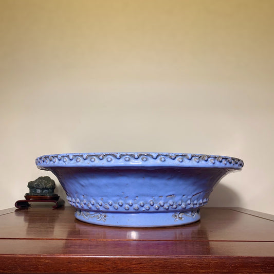 A wide, shallow blue glazed pot with a scalloped rim and raised dot decoration.