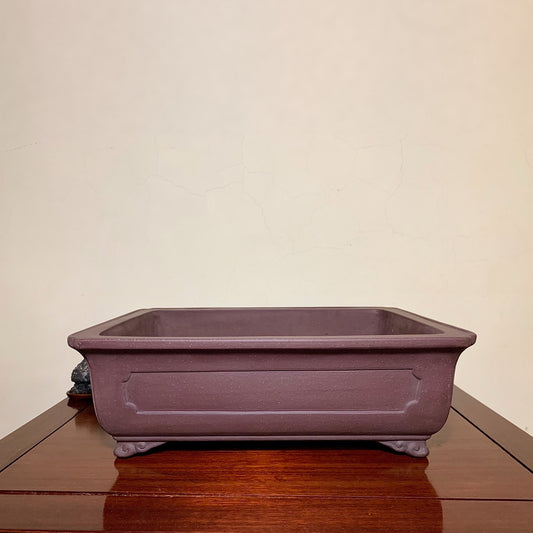 A matte purple rectangular pot with raised panel and four feet, unglazed surface.