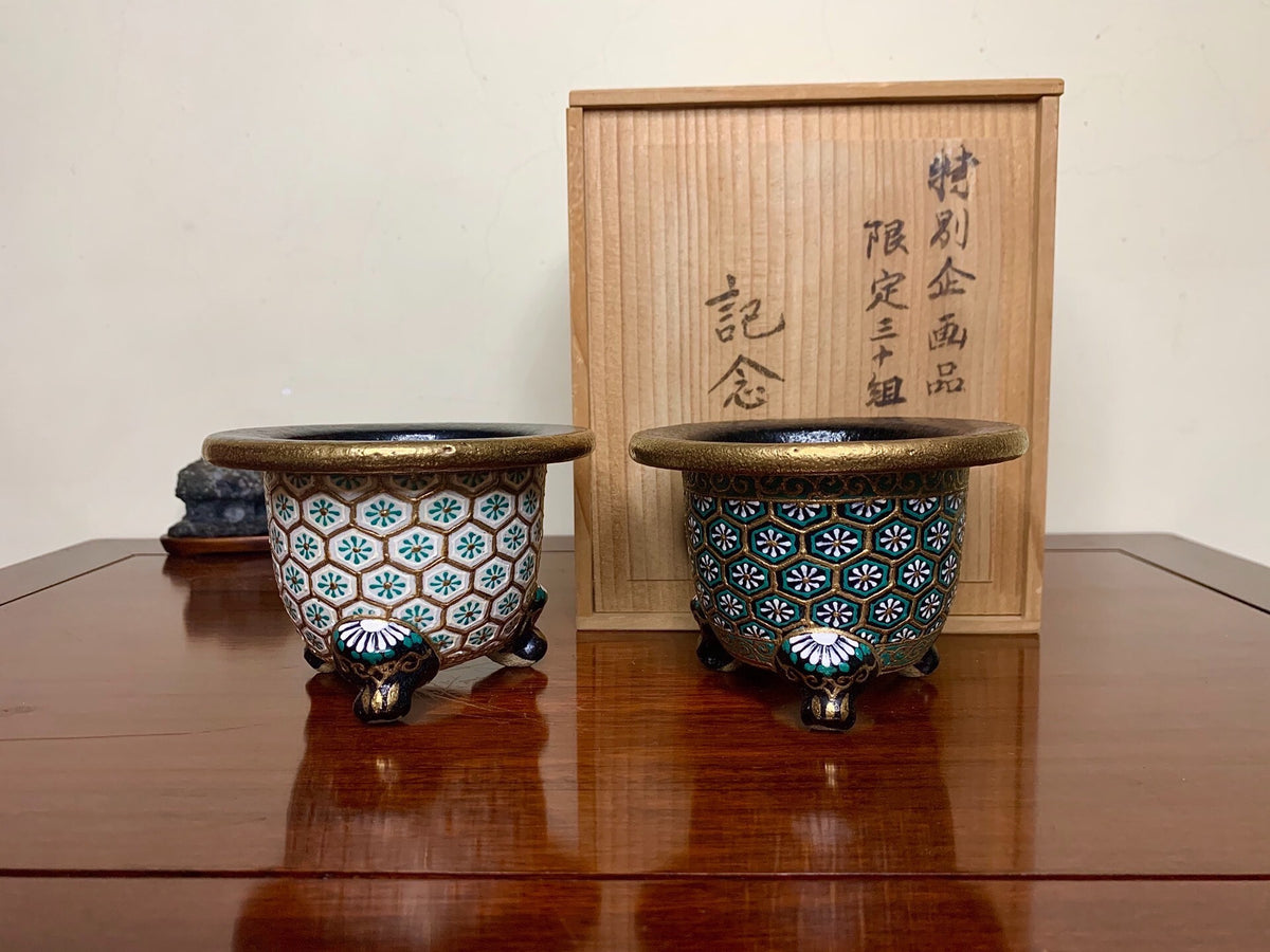 Two small, ornate pots with blue and white floral patterns on a glossy, glazed surface.