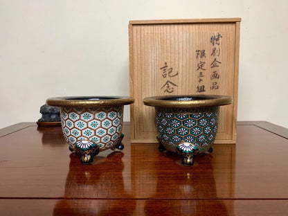 Two small, ornate pots with blue and white floral patterns on a glossy, glazed surface.