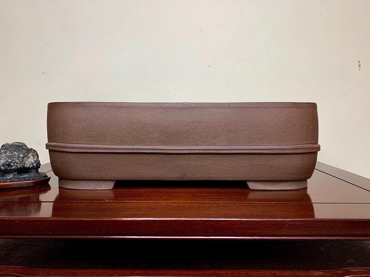 A matte brown rectangular pot with a textured surface and a single horizontal ridge.