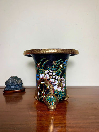 Dark blue glazed pot with gold rim, floral and wheel motifs, three ornate feet.