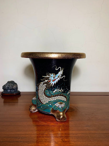 Black glazed pot with gold rim and foot, featuring a white and turquoise dragon on waves.